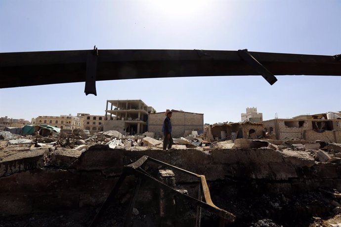 Archivo - Un hombre camina entre los restos de una explosión en Yemen.