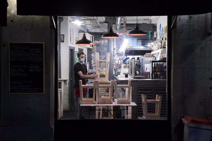 Archivo - Un trabajador recoge el interior de una cafetería de Madrid.