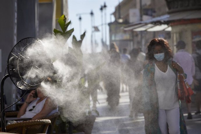 Varias personas caminan al lado de un difusor de vapor de agua de un restaurante de la calle Alcalá, a 2 de julio de 2021, en Madrid, (España).