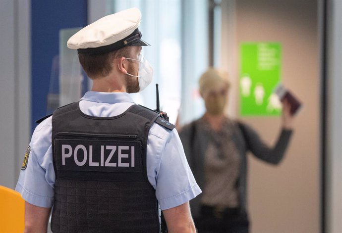 29 June 2021, Hessen, Frankfurt: A police officer stands to check passengers on a flight from Portugal at Frankfurt airport. As of today, the country is considered a virus variant area. After arriving in Germany, passengers must go into quarantine. Phot