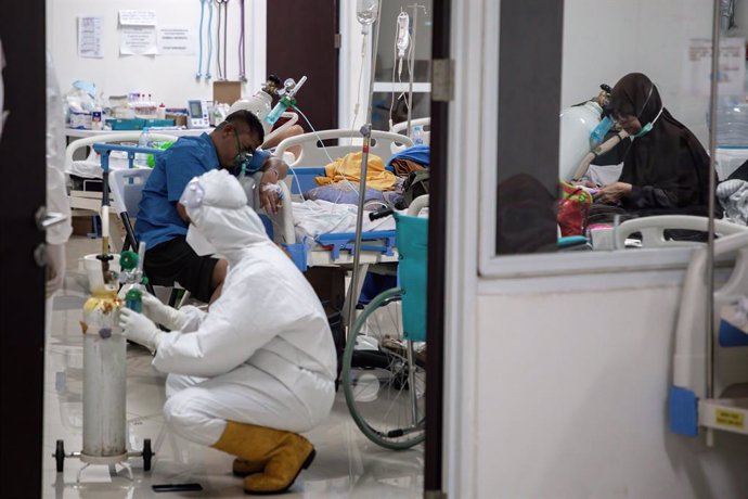 28 June 2021, Indonesia, Jakarta: A health worker wearing a Personal Protective suit fixes an oxygen cylinder next to a COVID-19 patient inside the Wisma Atlet Covid-19 Emergency Hospital complex. Photo: Risa Krisadhi/SOPA Images via ZUMA Wire/dpa