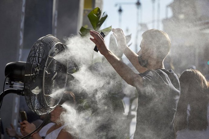 Un noi es refresca de la calor amb un difusor de vapor d'aigua