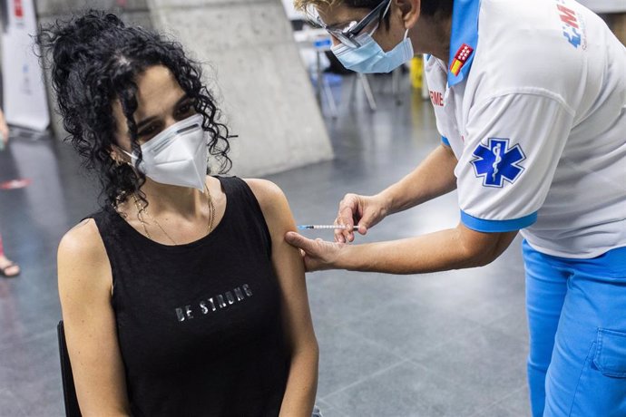 Un sanitario administra una dosis de la vacuna de Pfizer a una mujer en el Wizink Center durante la primera noche en la que el recinto está abierto a la vacunación, a 1 de julio de 2021, en Madrid (España).