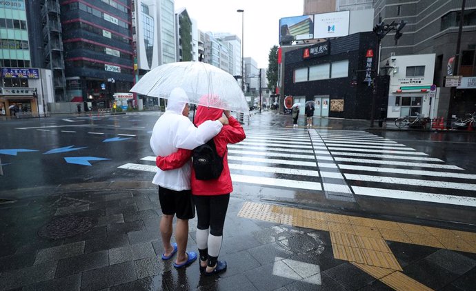Archivo - Una pareja se cubre con un paraguas en una calle de Tokio.
