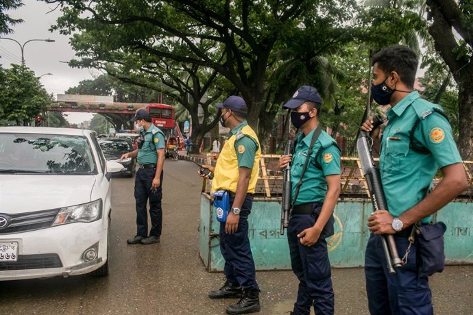 04 July 2021, Bangladesh, Dhaka: Police officers inspect a vehicle at a checkpoint in Dhaka during the covid-19 lockdown. Bangladesh is extending its current nationwide shutdown for seven more days with tighter restrictions to counter a rise in coronavi