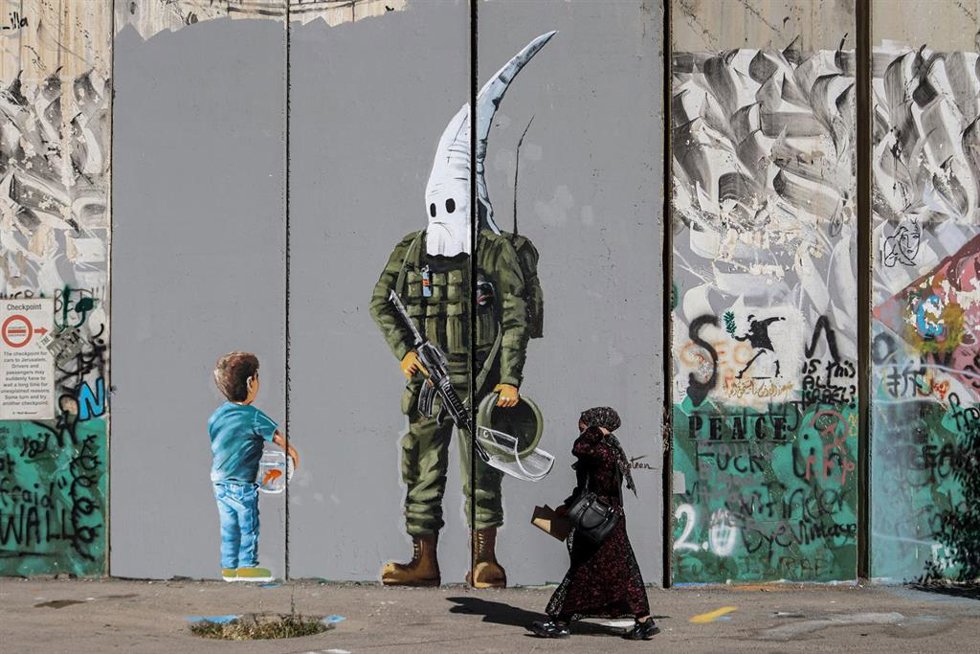 Archivo - Una mujer camina por delante de un mural en los territorios palestinos.