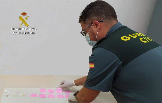 Un agente de la Guardia Civil junto a la 'cocaína rosa' incautada al detenido.