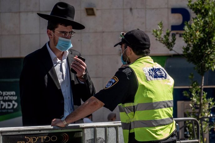 Archivo - Un policía de Israel junto a un hombre durante la pandemia de coronavirus