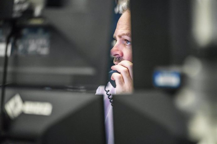 02 July 2021, Hessen, Frankfurt: A trader looks at his monitors in the trading room of the Frankfurt Stock Exchange with the telephone receiver to his ear. Photo: Frank Rumpenhorst/dpa