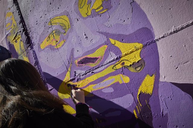Archivo - Una mujer participa en la tarea de pintar el mural feminista de Getafe.