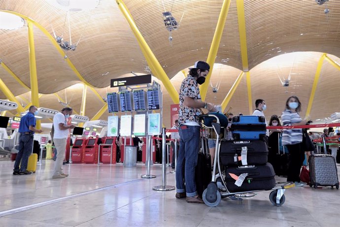 Varias personas con equipaje hacen cola en la T4 del aeropuerto Adolfo Suárez, Madrid-Barajas, en Madrid (España). 
