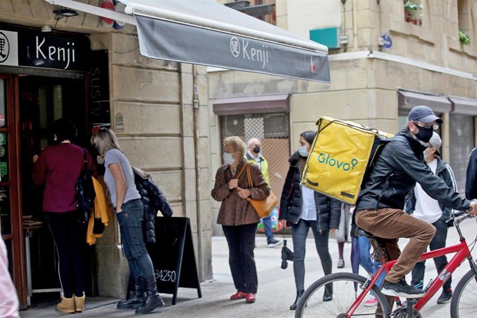 Archivo - Varias personas pasan al lado de un establecimiento en San Sebastián