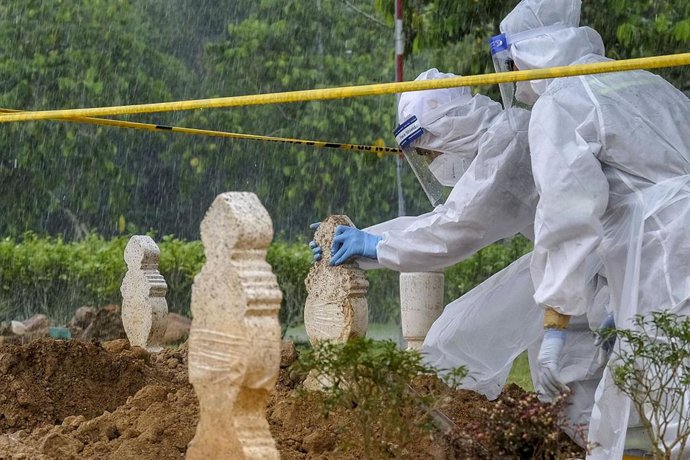 Trabajadores malayos poniendo tumbas en un cementerio a víctimas del coronavirus.