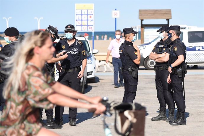 Varios agentes de Policía Local, preparan el desalojo de la playa de la Malvarrosa por la festividad de San Juan en Valncia