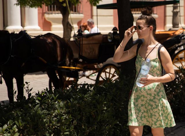 Turistas pasean por el centro de Sevilla provistos de gorras, abanicos y botellas de agua debido a que la capital andaluza ha superado los 40ªC y por ello se ha activado la alerta amarilla a 08 de junio del 2021, en Sevilla, Andalucía, España
