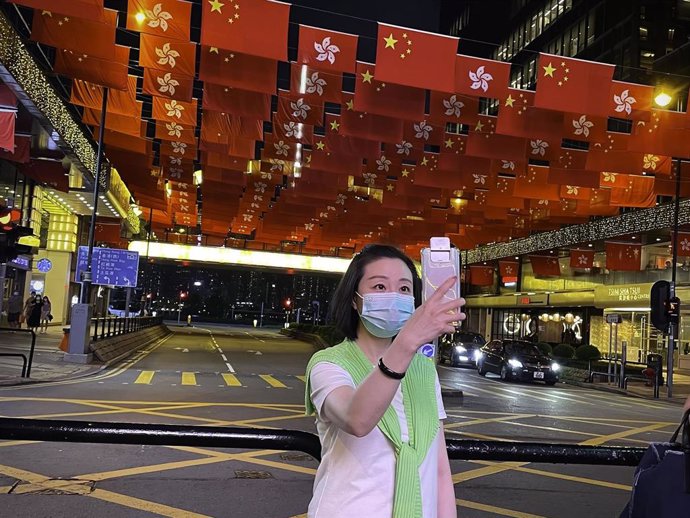 29 June 2021, China, Hong Kong: A woman takes a selfie near  China's national flags and the flags of the Hong Kong Special Administrative Region to mark the 24th anniversary of Hong Kong's handover to China. Photo: Dominic Chiu/SOPA Images via ZUMA Wire