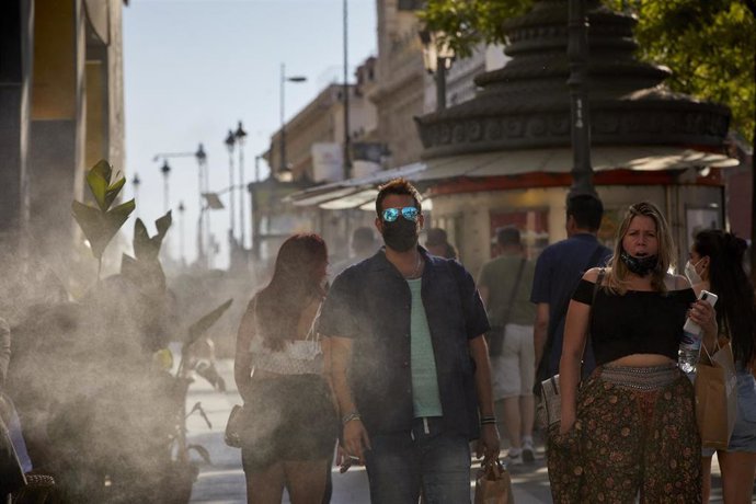 Varias personas caminan al lado de un difusor de vapor de agua de un restaurante de la calle Alcalá, a 2 de julio de 2021, en Madrid, (España). 