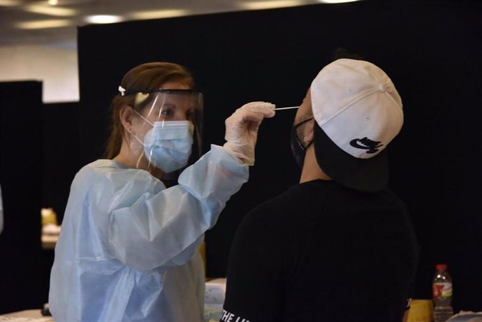 Una trabajadora sanitaria realiza un test de antígenos a un joven. 