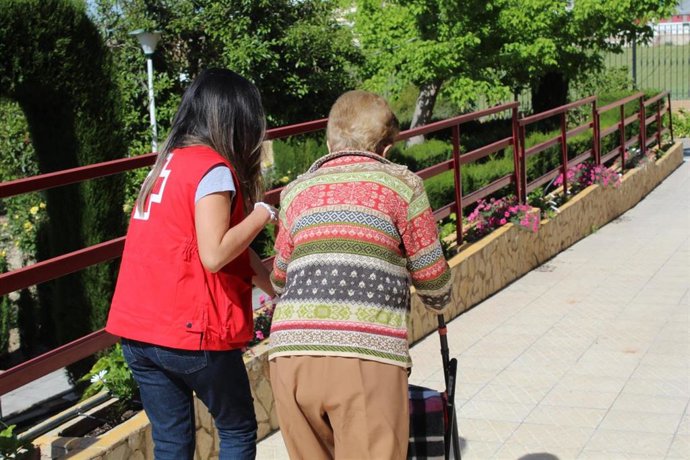 Archivo - Una voluntaria de Cruz Roja acompaña a una persona mayor.