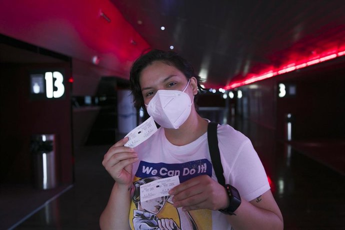 Archivo - Una mujer muestra su entrada en una sala de cine de Sevilla