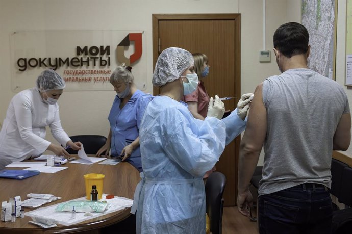 06 July 2021, Russia, Tambov: A nurse vaccinates an employee of the Multifunctional Center for the Provision of State and Municipal Services (the My Documents Center) with the Russian Gam-COVID-Vak coronavirus vaccine as many regions of Russia mandatory