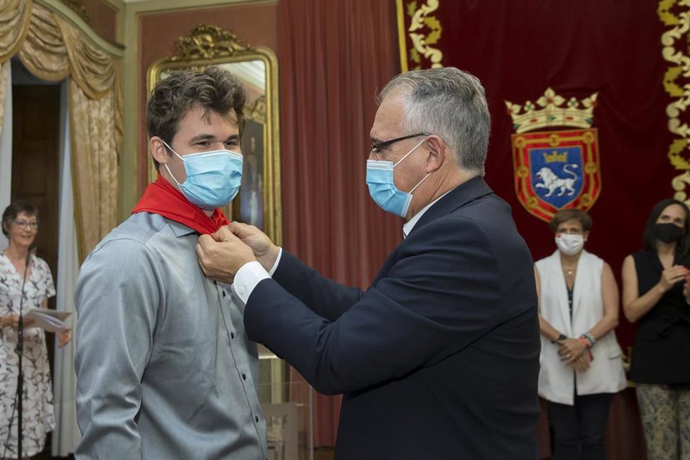 El alcalde de Pamplona, Enrique Maya, coloca un pañuelo de San Fermín al campeón de ajedrez Magnus Carlsen