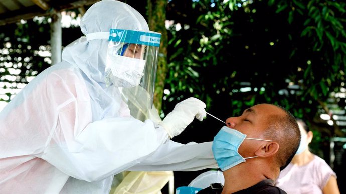Archivo - Una trabajadora sanitaria toma una muestra a un hombre para un test de coronavirus en la ciudad malasia de Sandakan
