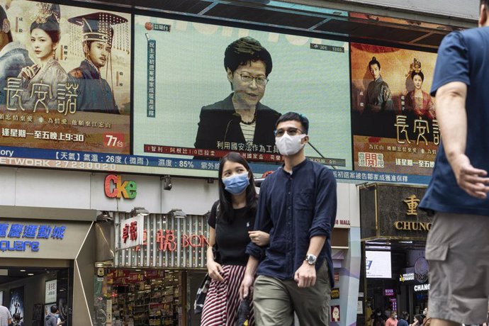 22 June 2021, China, Hong kong: Pedestrians walk past a screen reporting the news conference of Carrie Lam, Hong Kong's chief executive, in Tsim Sha Tsui district. Photo: Chan Long Hei/SOPA Images via ZUMA Wire/dpa