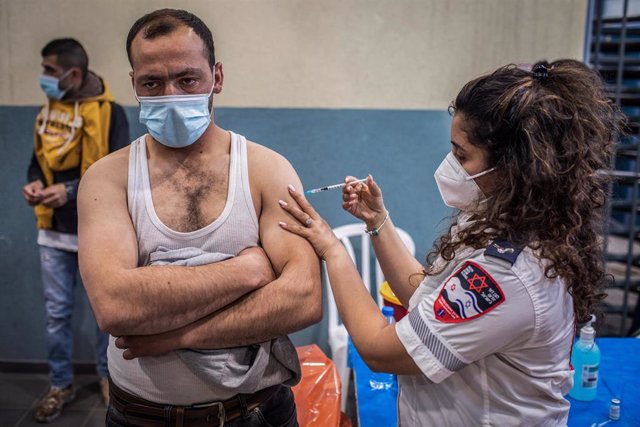 Archivo - Un trabajador palestino con permiso de trabajo en Israel recibe una dosis de la vacuna contra el coronavirus