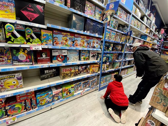 Archivo - Un niño mira junto a su padre un stand de juguetes en la sección de juguetes infantiles de un centro comercial de Madrid.