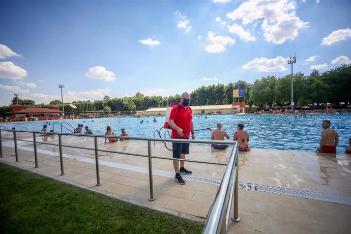 Un hombre desinfecta las zonas de la piscina del Parque Deportivo de Puerta de Hierro, el primer día de apertura de las piscinas para la temporada de verano, a 26 de junio de 2021, en Madrid (España). 