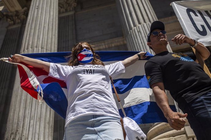 Varias personas se concentran sosteniendo banderas en el Congreso de los Diputados en apoyo a las movilizaciones contra el Gobierno cubano registradas ayer en la isla, a 12 de julio de 2021, en Madrid (España)