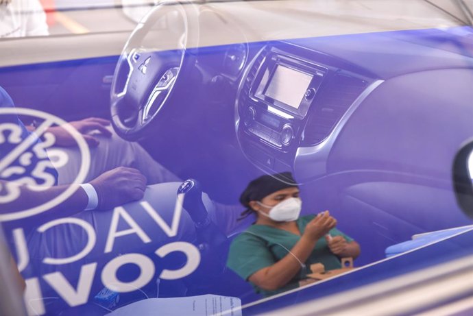 Archivo - 28 April 2021, El Salvador, San Salvador: A health worker is reflected on a car's window as she prepares a dose of the Chinese CoronaVac vaccine at a Covid-19 drive-thru vaccination facility. Photo: Camilo Freedman/SOPA Images via ZUMA Wire/dpa