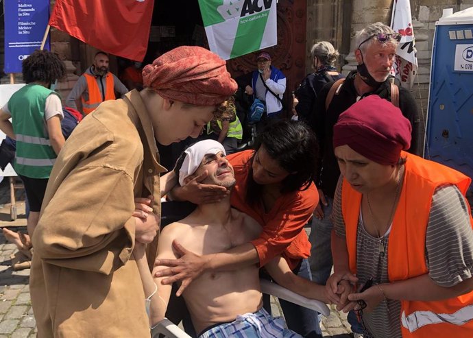 08 July 2021, Belgium, Brussels: A migrant is being cared for in front of the church "Saint-Jean-Baptiste au Beguinage". The church was occupied by undocumented people, some of whom have been on hunger strike since May in order to achieve collective reg