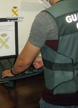 Un agente de la Guardia Civil muestra móviles recuperados en la operación
