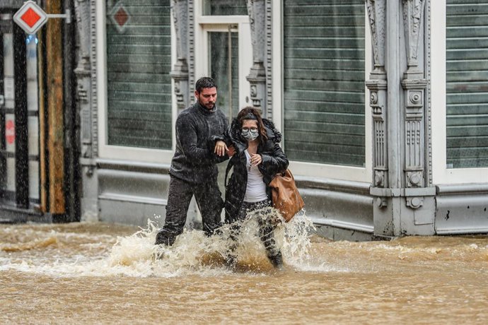 14 July 2021, Belgium, Spa: A man helps a woman to cross a flooded street amid heavy rains. Photo: Bruno Fahy/BELGA/dpa
