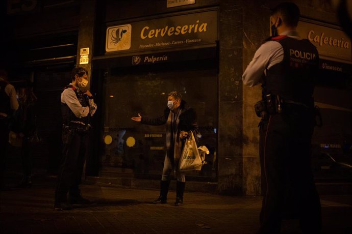 Archivo - Varios mossos d'Esquadra paran a una persona durante un control durante el toque de queda impuesto por la crisis sanitaria del Covid-19 desde las 22.00 horas a las 6.00 del día siguiente, en Barcelona, Catalunya, (España), a 6 de noviembre de 