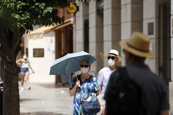 Varias personas intentan protegerse del calor en el día donde la capital andaluza se encuentra  en  aviso naranja por temperaturas que superarán los 40 grados en algunos puntos de la capital y la provincia a 12 de julio del 2021 en Málaga (Andalucía). S