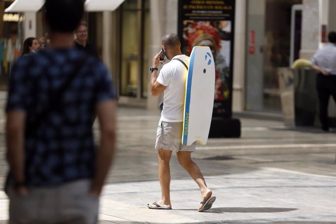 Varias personas intentan protegerse del calor en el día donde la capital andaluza se encuentra  en  aviso naranja por temperaturas que superarán los 40 grados en algunos puntos de la capital y la provincia a 12 de julio del 2021 en Málaga (Andalucía). S