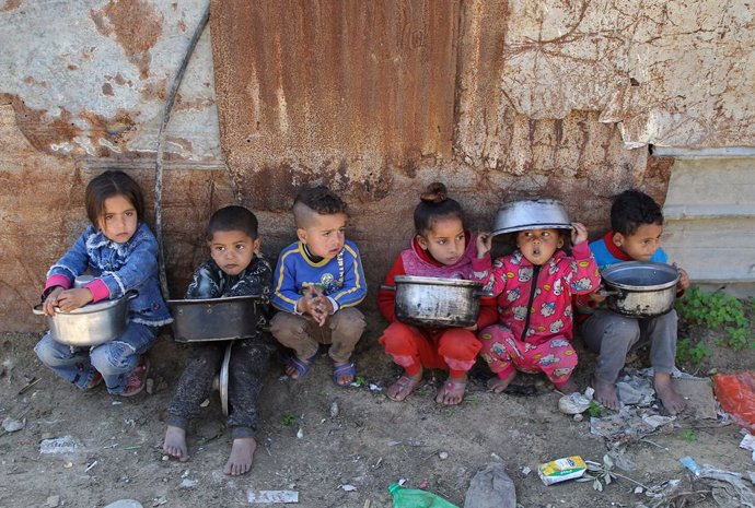 Niños palestinos esperan para recibir comidas benéficas en el barrio de Al Zaitún, en el este de la ciudad de Gaza