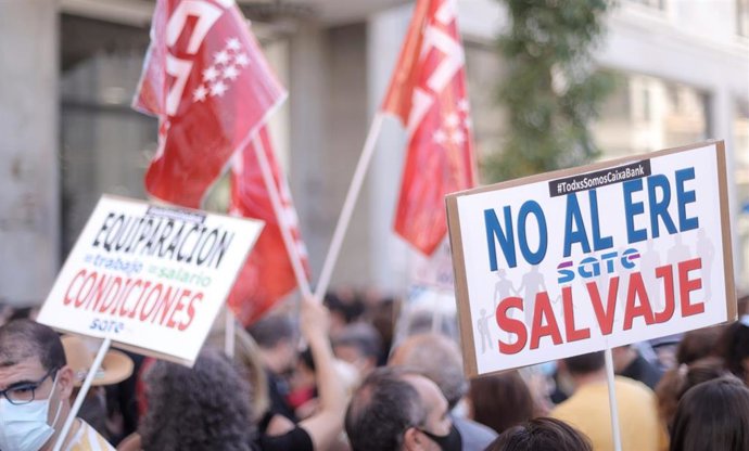 Un grupo de personas levanta pancartas durante una concentración de trabajadores de Caixabank frente al Hotel Riu Plaza España durante su segunda jornada de huelga, a 29 de junio de 2021, en Madrid (España). La plataforma de unidad sindical, conformada 