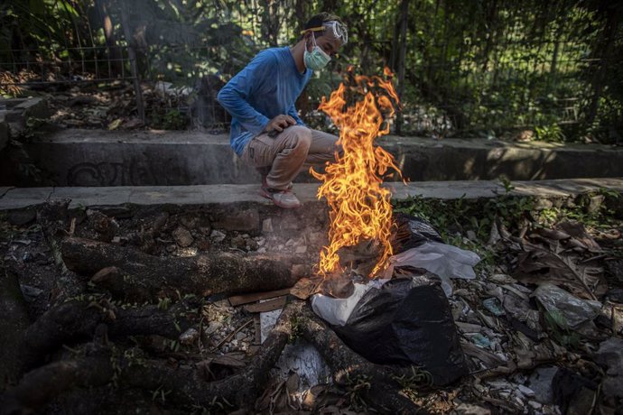 09 July 2021, Indonesia, Bogor: A man cremates a body of a Covid-19 victim who died outside the hospital in Bogor, West Java. Photo: Donal Husni/ZUMA Wire/dpa