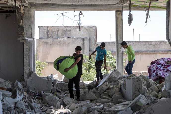 Varios niños recuperan bienes de su vivienda tras un ataque del Ejército de Siria contra la provincia de Idlib
