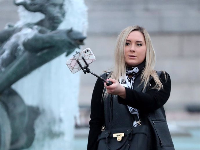 Archivo - A woman takes a selfie photograph on a smartphone in front of the frozen fountains of Trafalgar Square on February 11, 2021 in London, England.