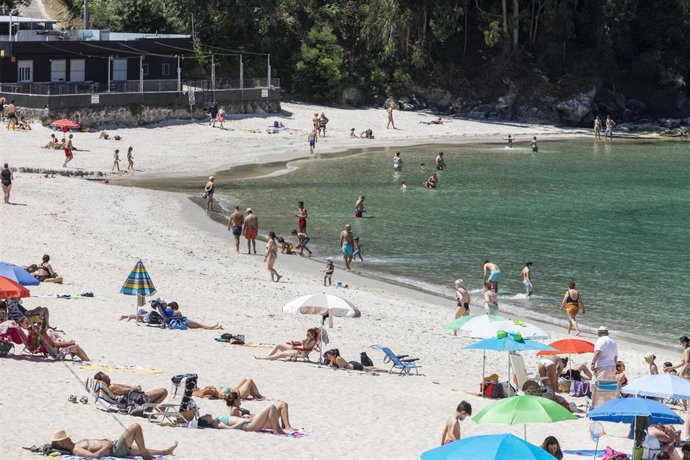Archivo - Varias personas se bañan y toman el sol en una playa del municipio de Marín, en Pontevedra