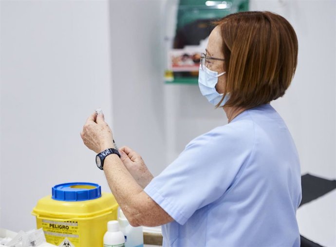 Archivo - Una trabajadora sanitaria sostiene una jeringuilla 