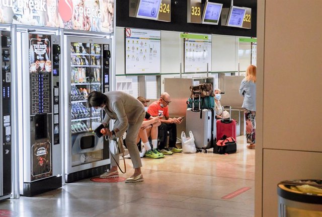 Una mujer saca bebida de una máquina expendedora, en la terminal T1 del Aeropuerto Adolfo Suárez Madrid-Barajas.