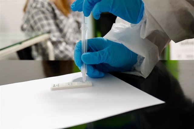 Archivo - Una trabajadora sanitaria sostiene un test de antígenos
