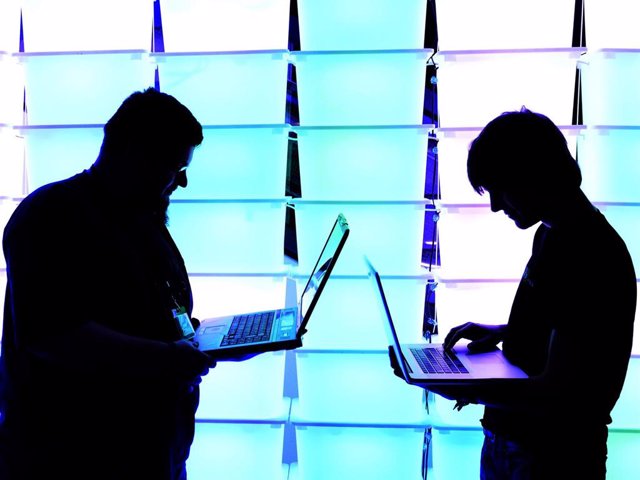 Archivo - Dos personas sostienen sus portátiles durante un congreso de hackers en Alemania.
