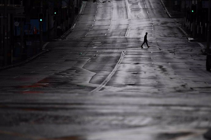 FILED - 29 June 2021, Australia, Sydney: A pedestrian crosses an empty Bridge Street in Sydney. More than five million people in Greater Sydney and its surrounds have gone into a 14-day lockdown as health authorities try to regain control of a coronavir